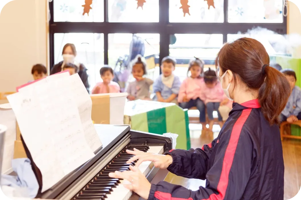 senju保育園の保育者がピアノを弾いて園児達が歌をうたっている様子