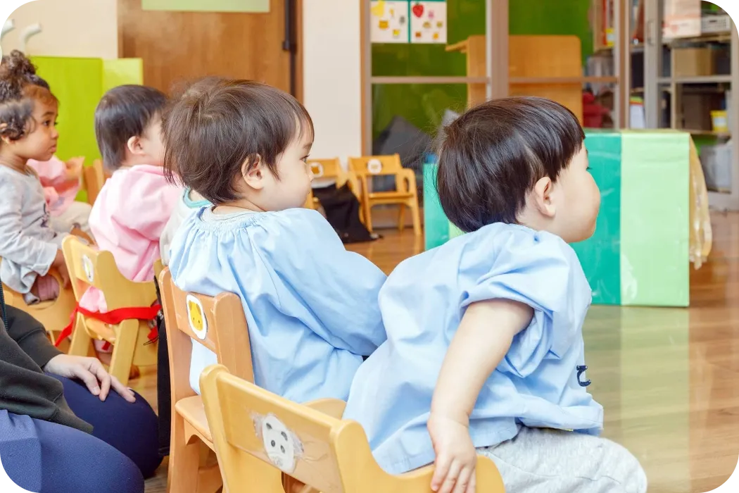 室内に並べてある椅子に座るsenju保育園の園児達